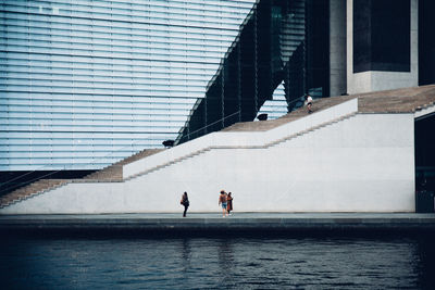 People on swimming pool against buildings in city
