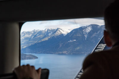 Rear view of man looking through boat window