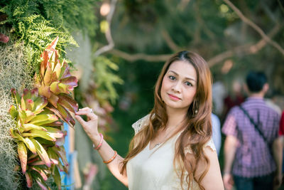 Portrait of smiling young woman against plants