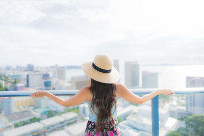 Rear view of woman standing against sky in city