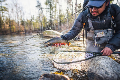 A man prepares to release a brook trout in maine