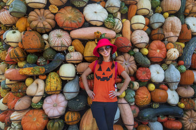 Portrait of smiling woman wearing sunglasses standing against pumpkins