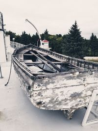 Abandoned boat moored on shore against sky