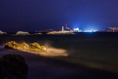 Rocks in sea against sky at night