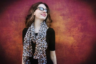 Smiling young woman standing against wall