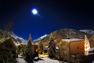 Snow covered buildings against sky at night