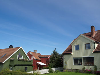 Houses amidst trees and buildings against blue sky