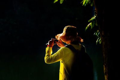 Woman photographing in forest using smart phone