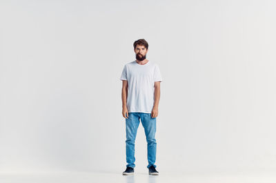 Portrait of young man standing against white background