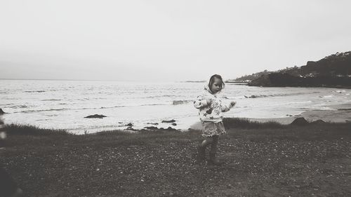 Boy standing on beach against clear sky