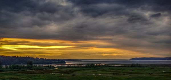 Scenic view of sea against dramatic sky during sunset