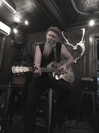 Portrait of man playing guitar while singing in recording studio