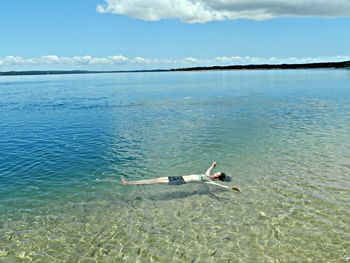 Man swimming in sea against sky