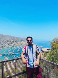 Portrait of young man standing against blue sky