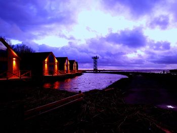 Silhouette lighthouse by sea against sky