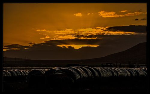 Scenic view of mountains against cloudy sky at sunset