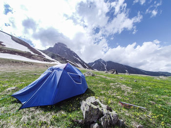 Tent on field by mountain against sky