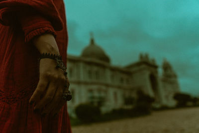 Midsection of woman standing by building against sky