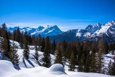 Scenic view of snow covered mountains against blue sky