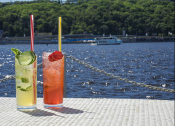 Close-up of lemonades in glasses on pier against sea