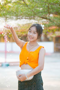 Portrait of young woman standing against trees