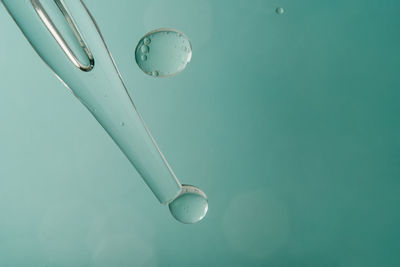 Pipette with cosmetic product in water with bubbles.