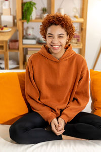 Portrait of young woman sitting on sofa at home