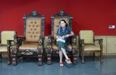 Portrait of young woman standing against red wall