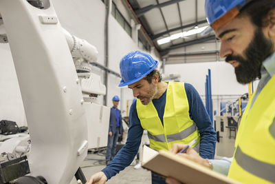 Engineers working on robotic arm in industry