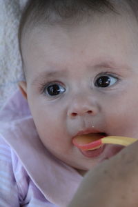 Close-up of cute baby girl lying on bed 