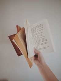 Cropped hand holding books against grey background 