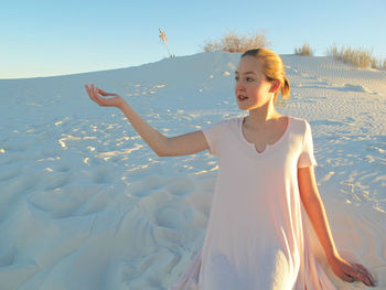 Young woman looking away while gesturing at white sands national monument during sunset