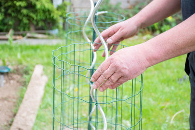 Cropped image of man putting fence around plant