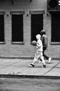 Side view of male friends walking on sidewalk in city