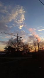 Bare trees against sky at sunset