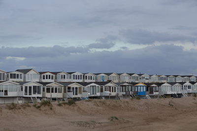 Beach huts by buildings against sky