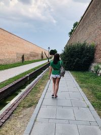 Rear view of woman walking on footpath against sky