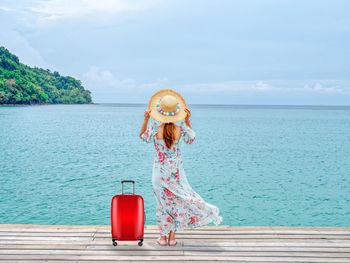 Woman standing by sea against sky