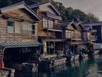 Houses by river against buildings in city