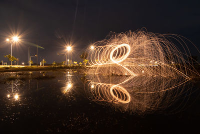 Light trails in lake against sky at night