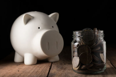 Coins in container by piggy bank on table