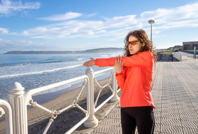 Woman standing by railing against sea