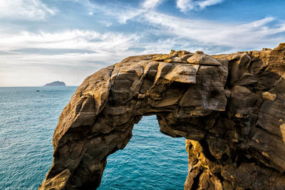 Rock formation by sea against sky