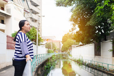 Young woman standing by canal in city