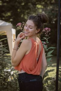 Side view of smiling young woman with eyes closed standing by plants