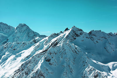 Scenic view of snow covered mountains against clear blue sky
