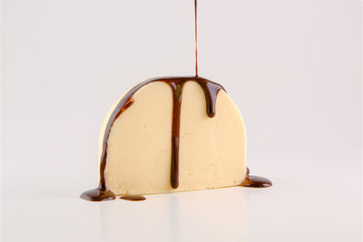 Close-up of ice cream hanging over white background
