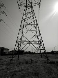 Low angle view of electricity pylon on field against sky