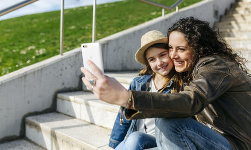 Happy mother and daughter taking a selfie on stairs