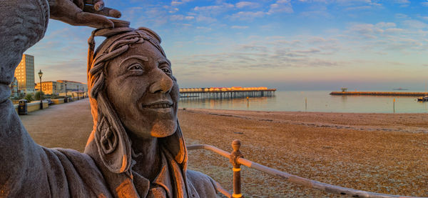 Close-up of statue by sea against sky during sunset